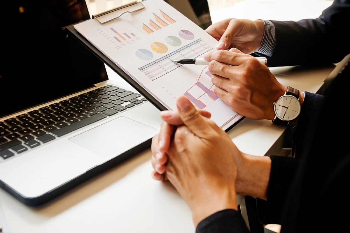 Manager reviewing financial reports and charts with a laptop