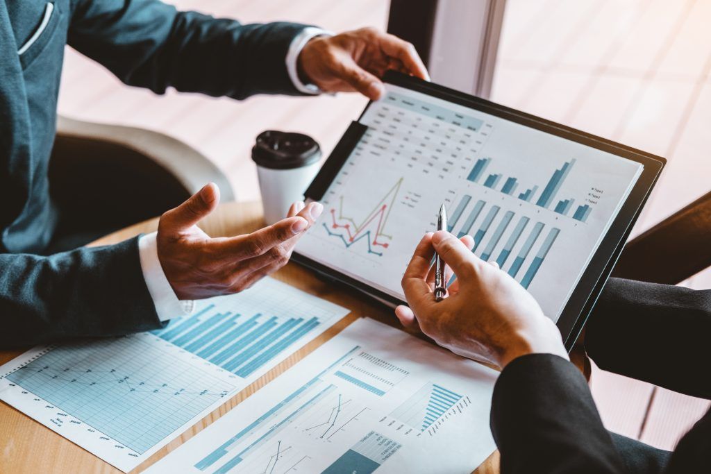 Colleagues reviewing financial dashboards and reports on a tablet
